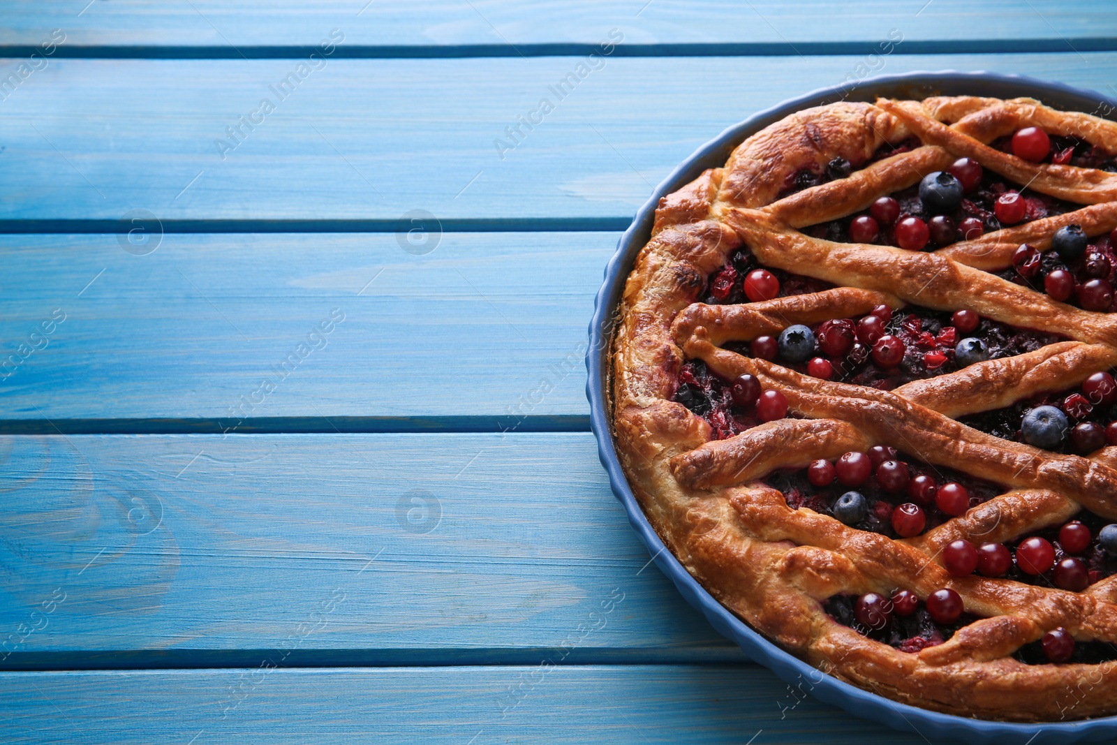 Photo of Delicious currant pie and fresh berries on blue wooden table, closeup. Space for text