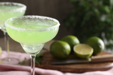 Photo of Delicious Margarita cocktail in glasses on table, closeup. Space for text