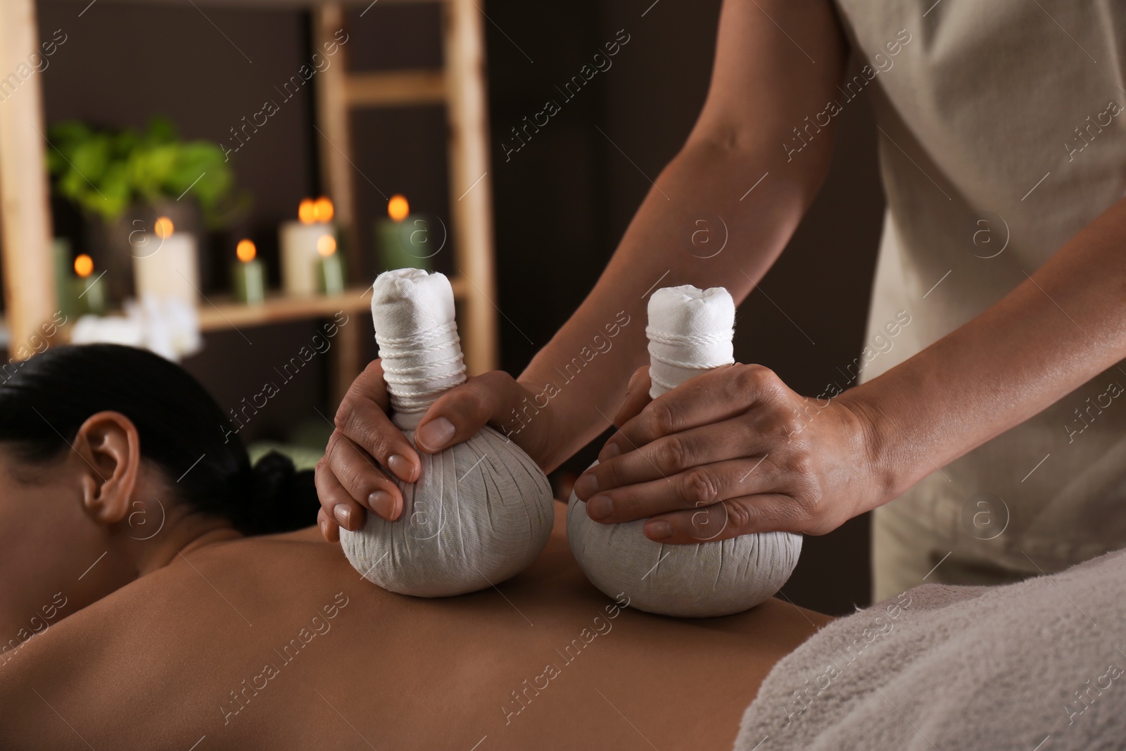 Photo of Young woman receiving herbal bag massage in spa salon, closeup