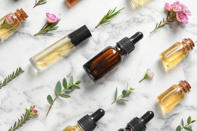 Photo of Flat lay composition with bottles of natural tea tree oil on white marble background