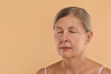 Woman with closed eyes on beige background, space for text