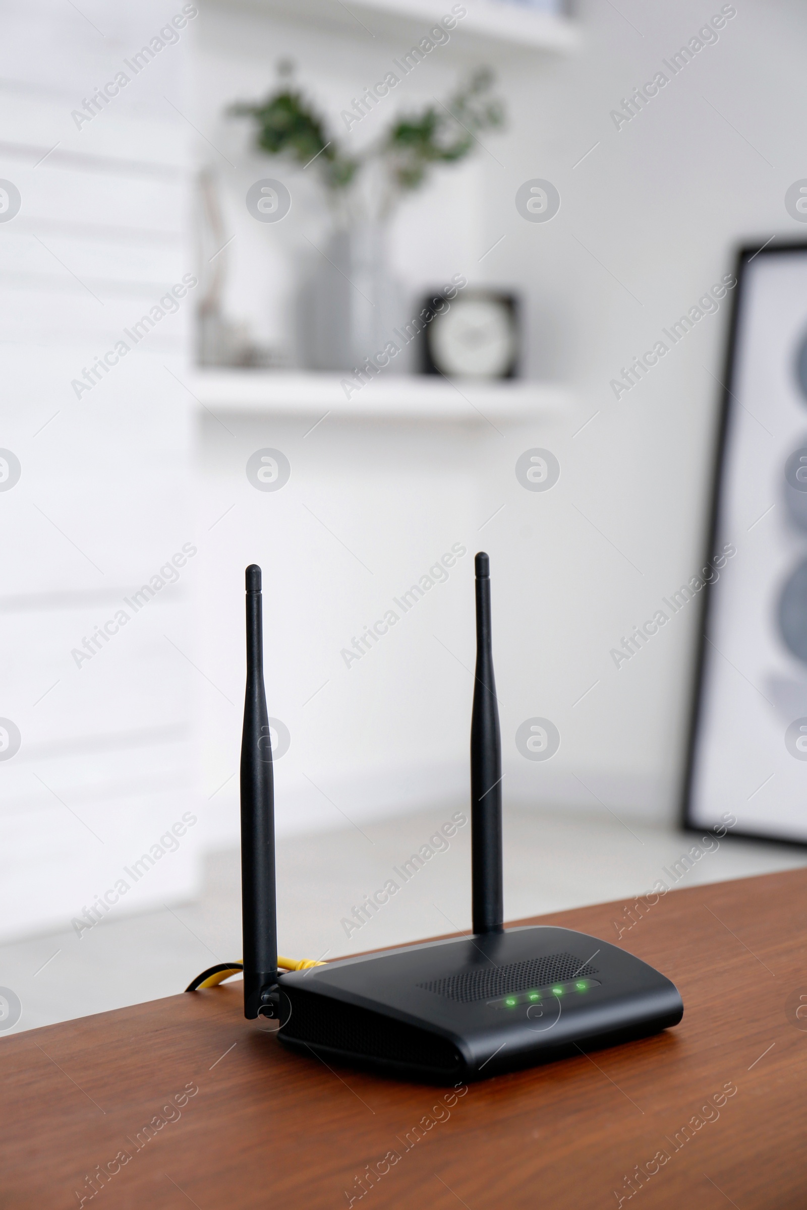 Photo of Modern Wi-Fi router on wooden table indoors