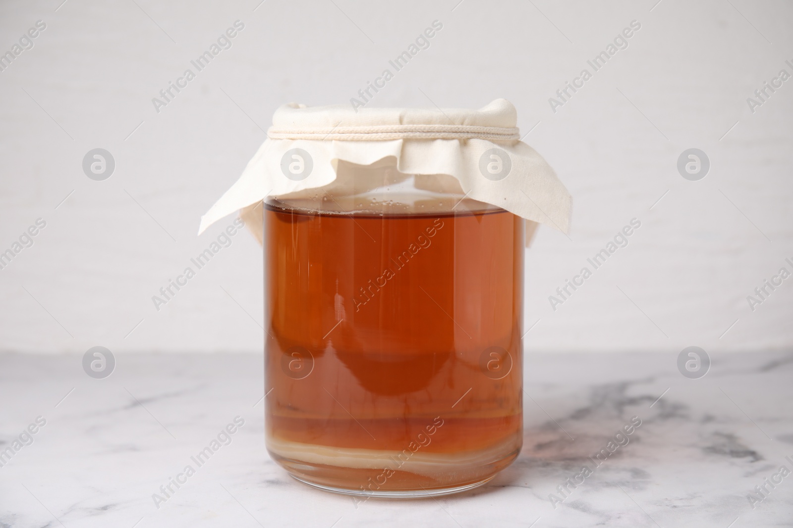 Photo of Tasty kombucha in glass jar on white marble table