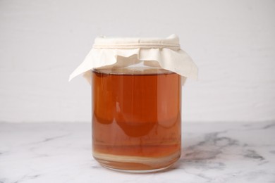 Photo of Tasty kombucha in glass jar on white marble table