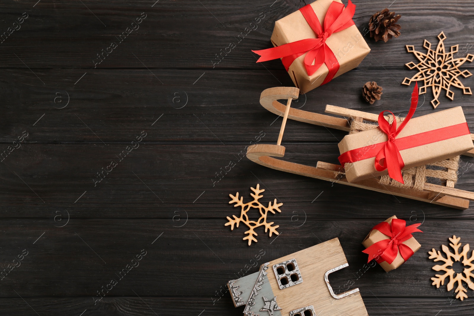 Photo of Beautiful Christmas composition with miniature sleigh on black wooden table, flat lay. Space for text