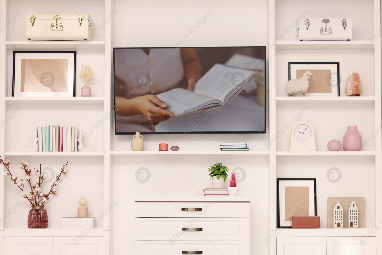 Photo of TV and shelves with different decor in room. Interior design