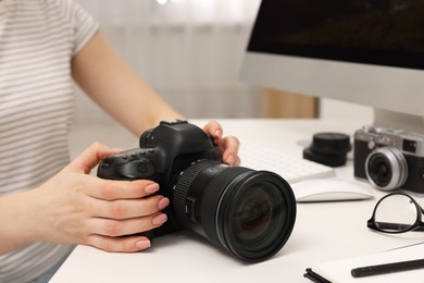 Photographer with camera at white table indoors, closeup