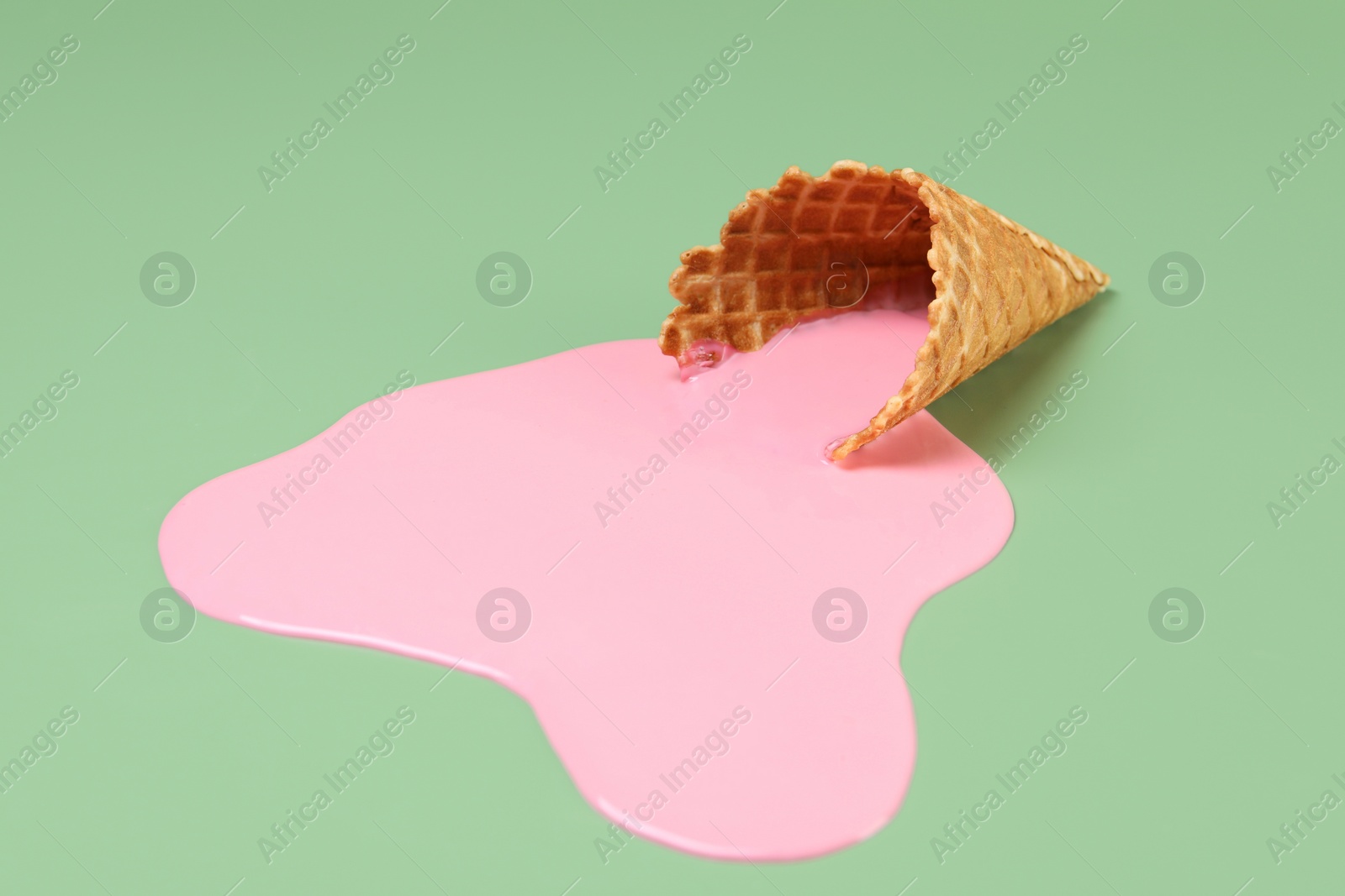 Photo of Melted ice cream and wafer cone on green background