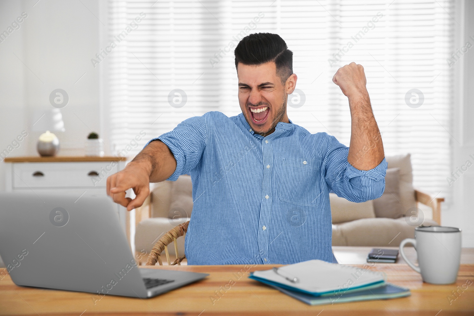 Photo of Emotional man participating in online auction using laptop at home