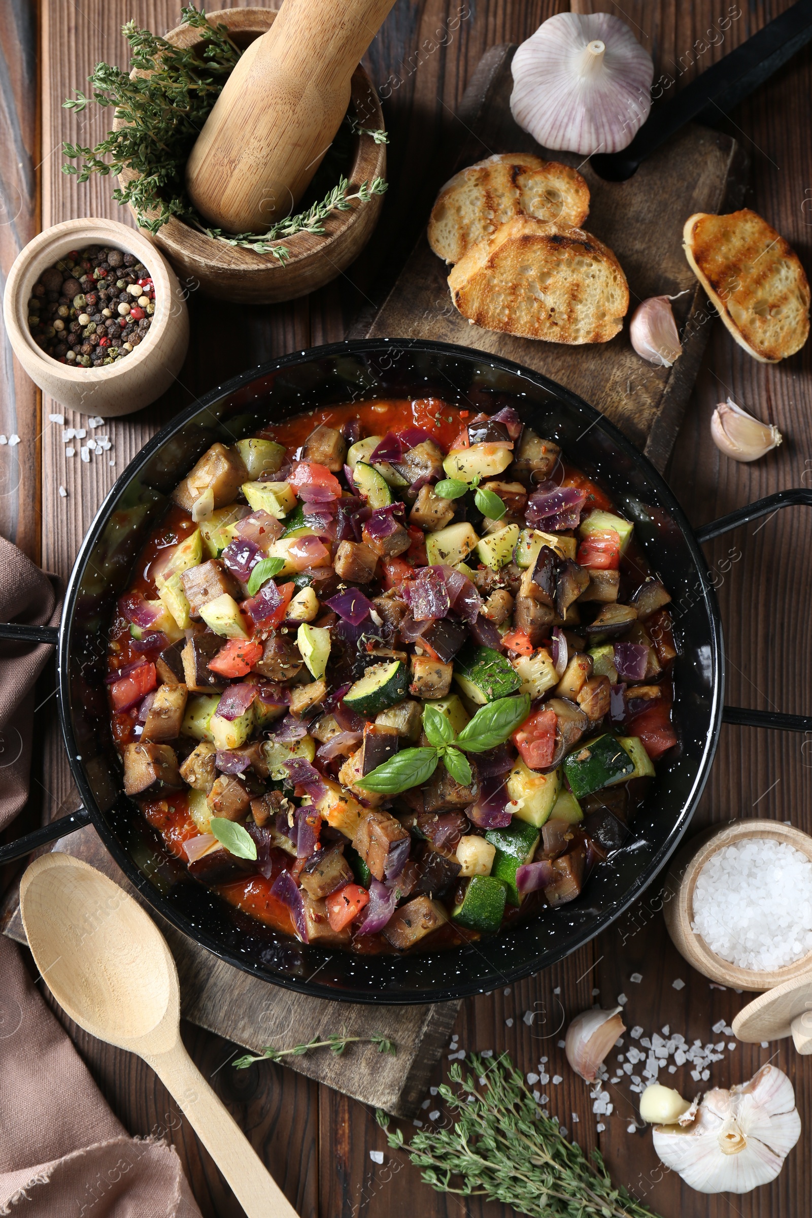 Photo of Delicious ratatouille in baking dish served on wooden table, flat lay