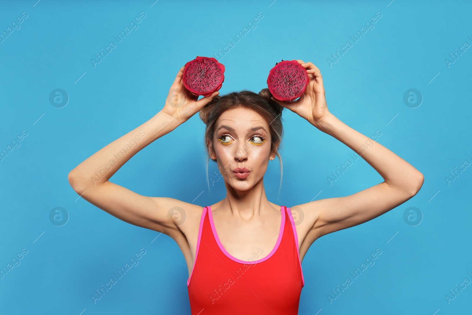 Photo of Young woman with fresh pitahaya on light blue background. Exotic fruit