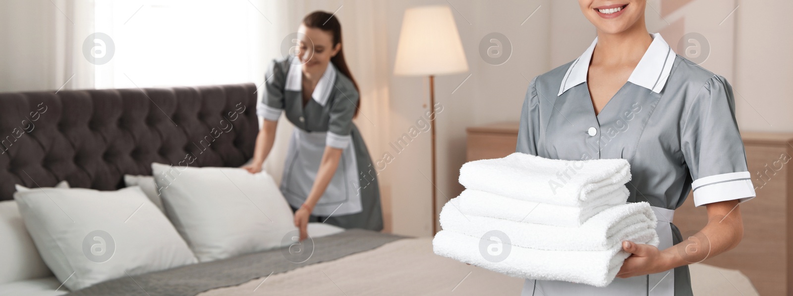 Image of Chambermaid with stack of fresh towels in hotel room, closeup view with space for text. Banner design