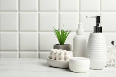 Photo of Different bath accessories and personal care products on white table near tiled wall, space for text