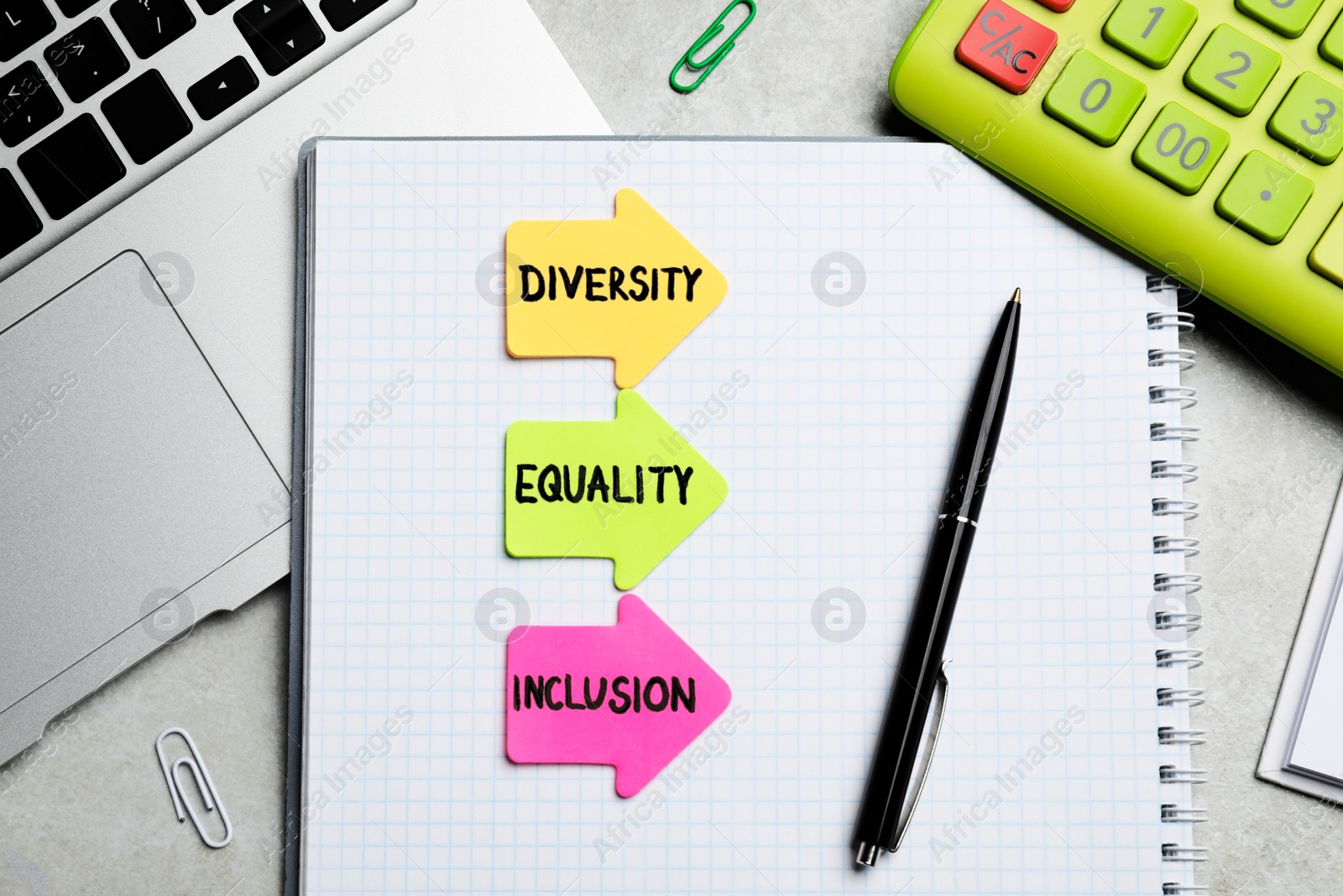 Photo of Sticky notes with words Diversity, Equality, Inclusion, laptop and stationery on grey table, flat lay