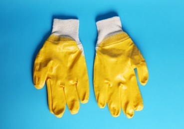 Photo of Gardening gloves on light blue background, top view