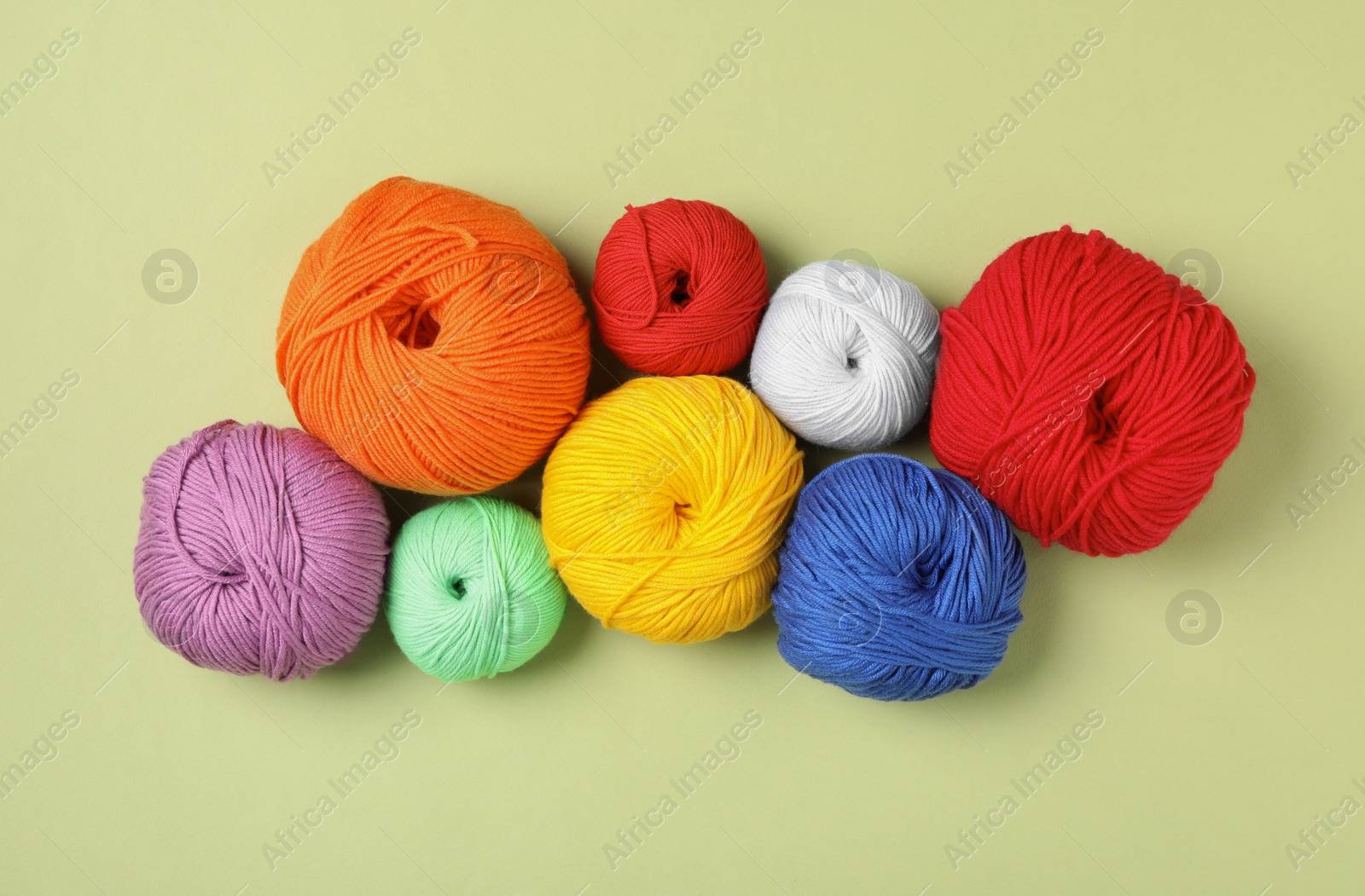 Photo of Soft woolen yarns on green background, flat lay
