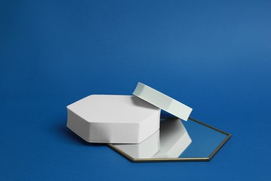 Photo of Product photography props. Hexagonal shaped podiums and mirror on blue background