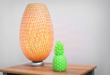 Photo of Pineapple shaped candle and lamp on table in room