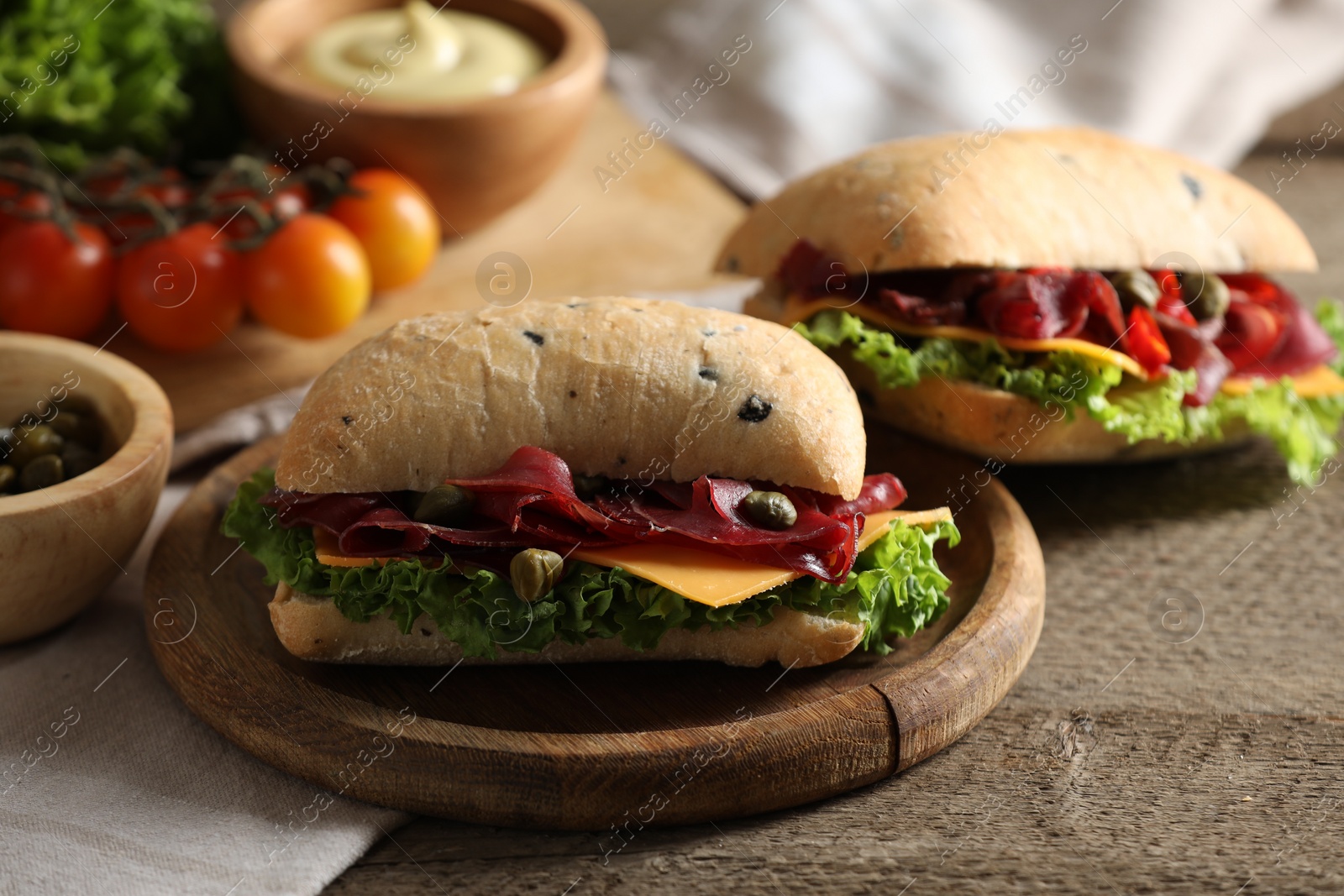 Photo of Delicious sandwiches with bresaola, lettuce and cheese on wooden table