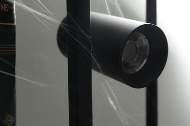 Photo of Cobweb on lamp against gray background, closeup