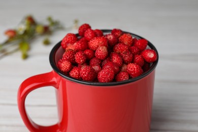 Fresh wild strawberries in mug on white table, closeup