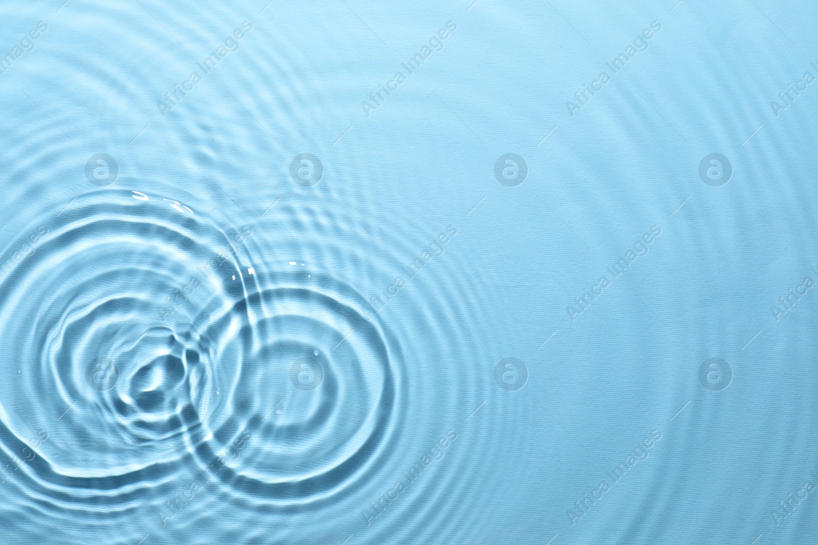 Photo of Rippled surface of clear water on light blue background, top view