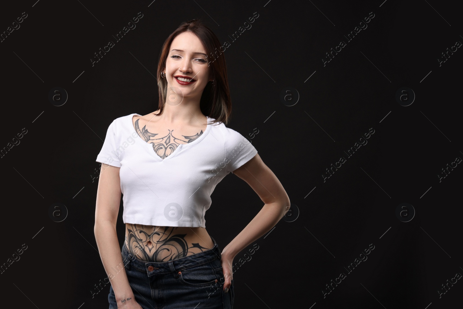 Photo of Portrait of smiling tattooed woman on black background. Space for text