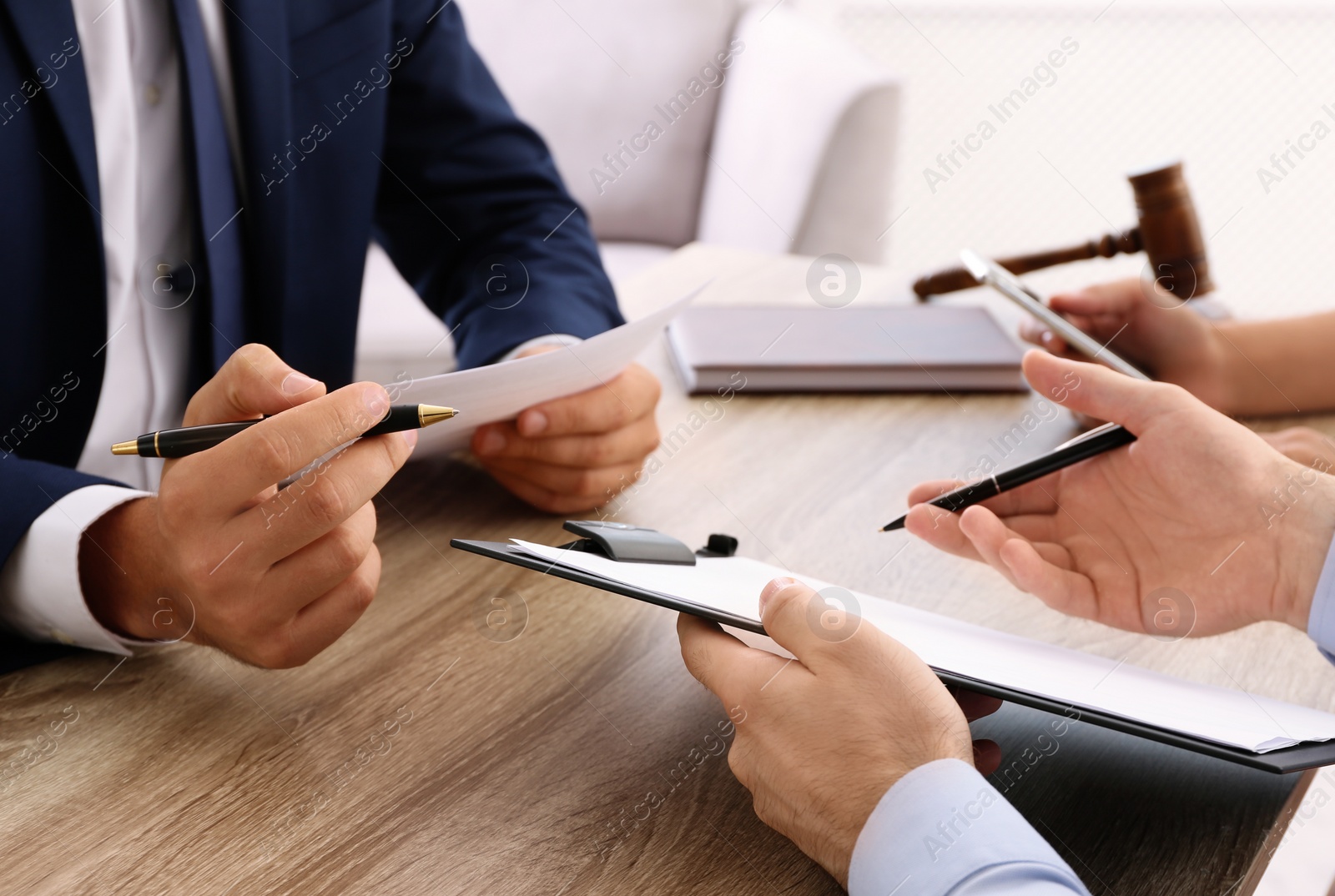 Photo of Lawyer working with clients at table in office, focus on hands