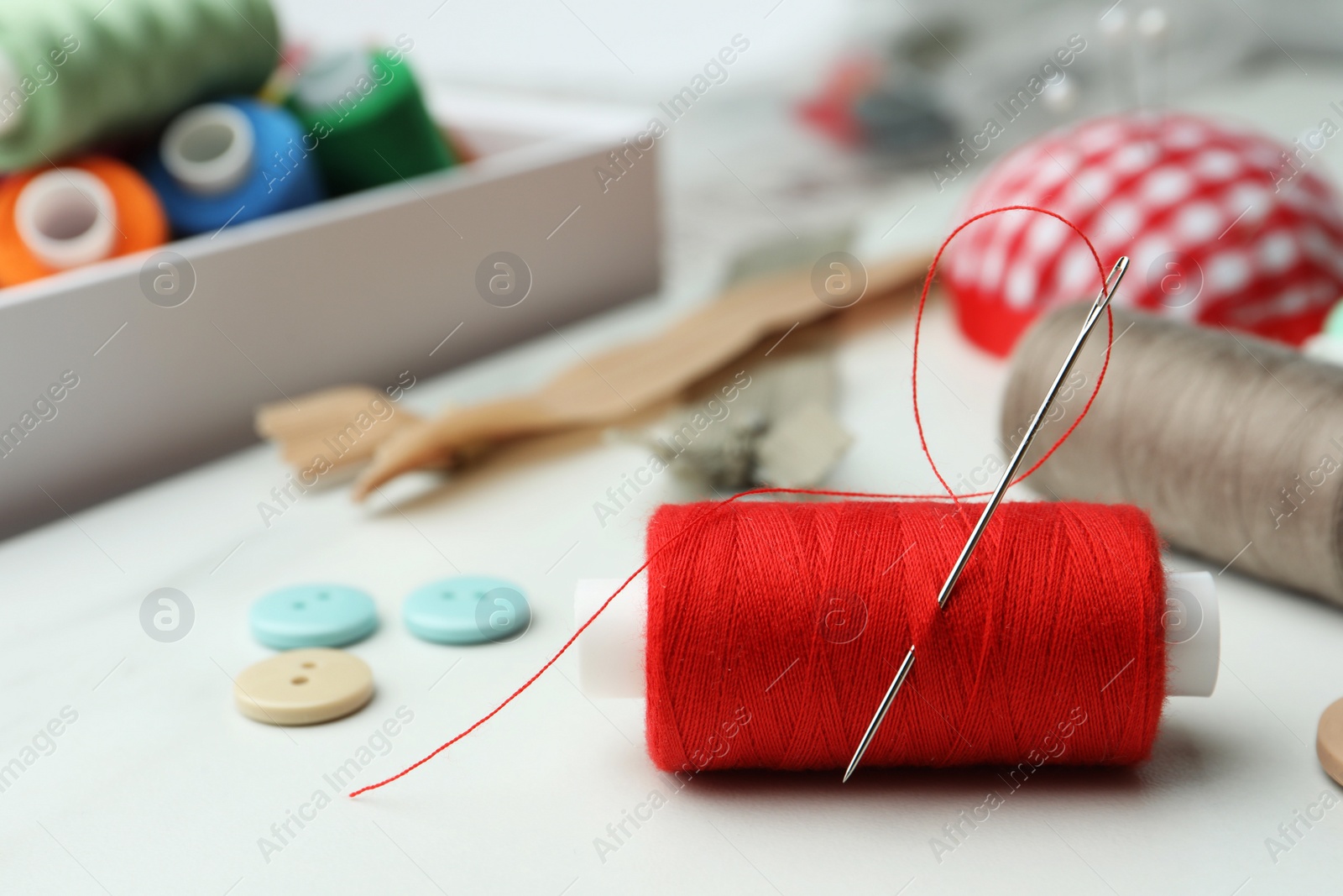 Photo of Threads and other sewing supplies on white marble table