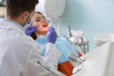 Photo of Closeup view of professional dentist's equipment and blurred doctor with patient on background. Space for text
