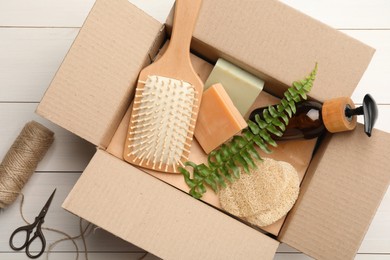 Photo of Cardboard box with eco friendly products on white wooden table, flat lay