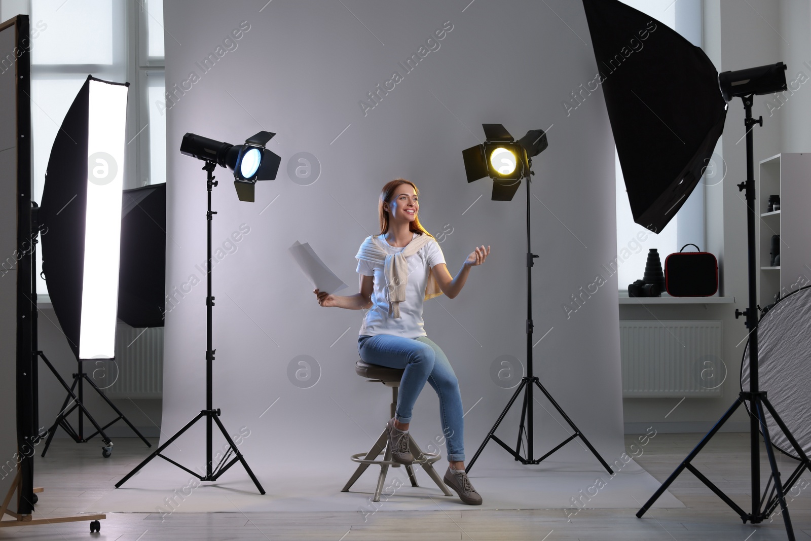 Photo of Casting call. Young woman with script performing on grey background in modern studio