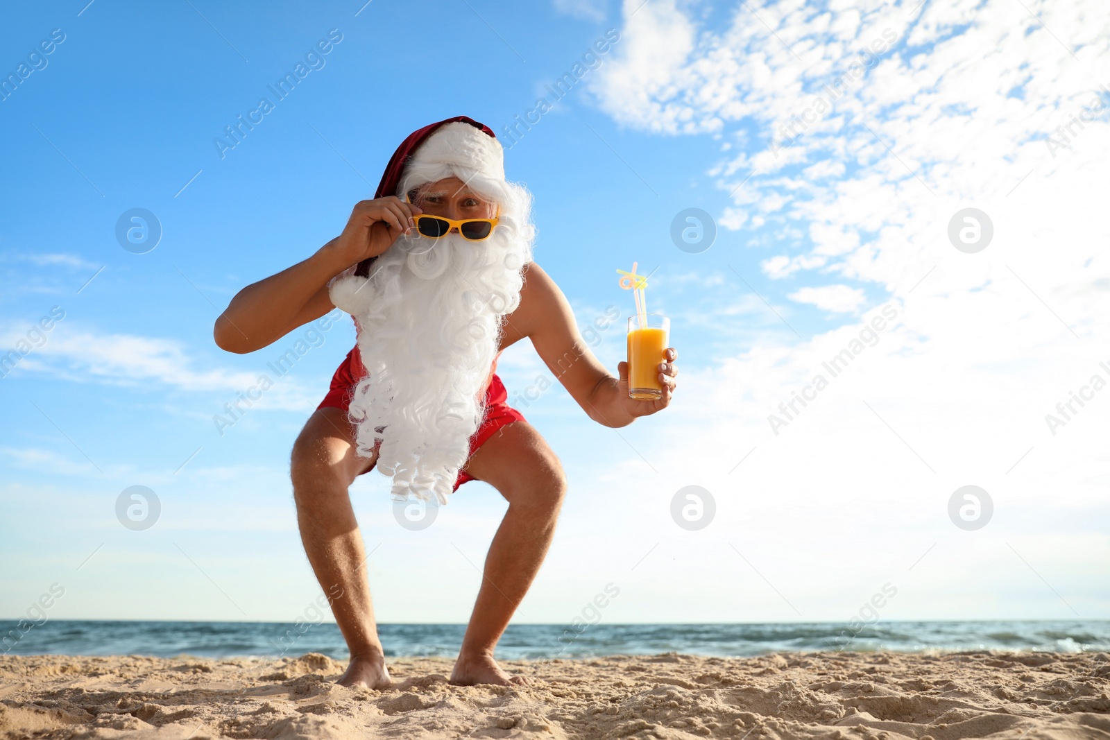 Photo of Santa Claus with cocktail on beach, space for text. Christmas vacation