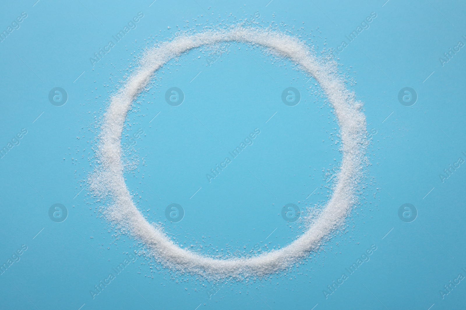 Photo of Frame made of granulated sugar on light blue background, top view. Space for text