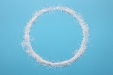 Photo of Frame made of granulated sugar on light blue background, top view. Space for text