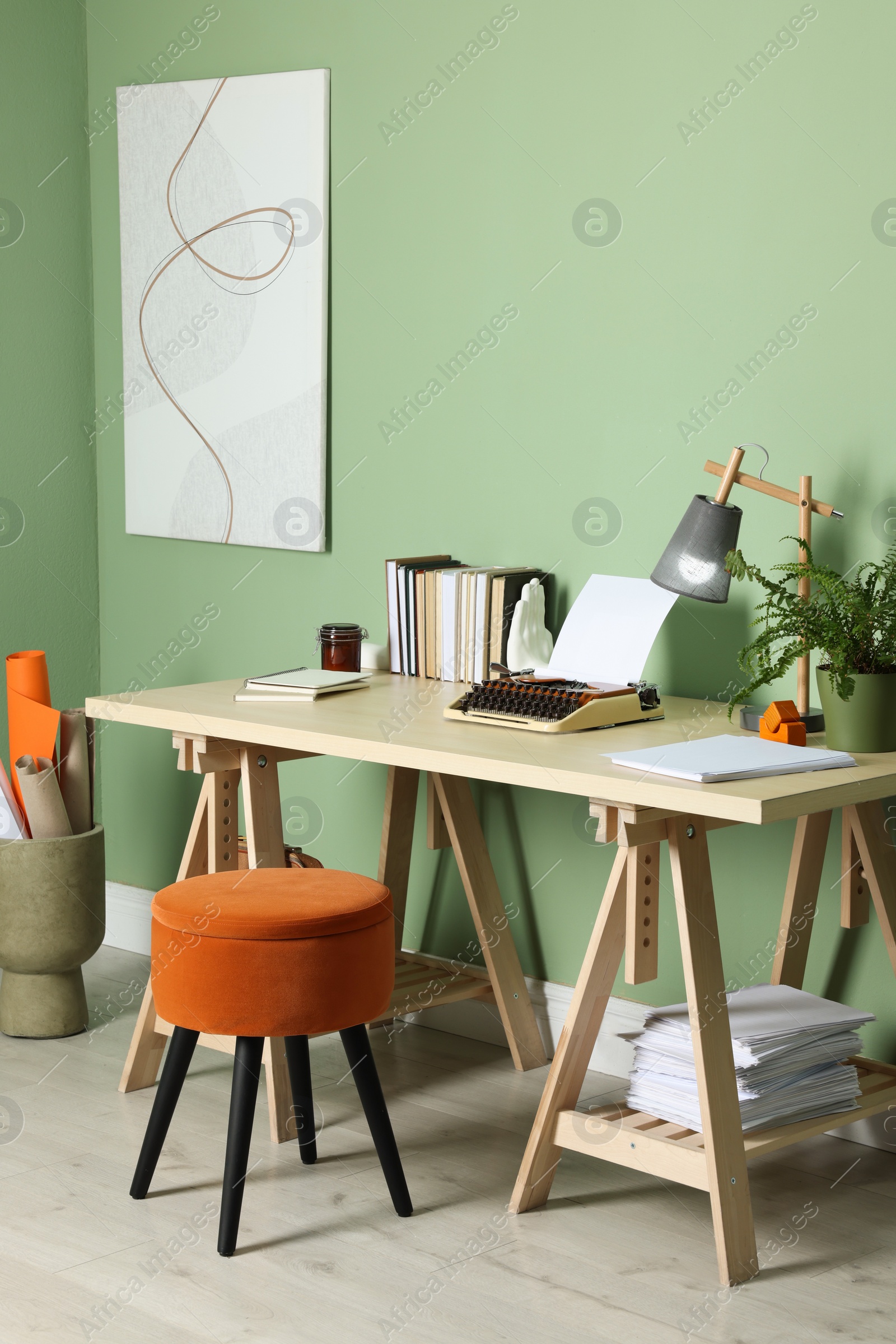 Photo of Writer's workplace with typewriter on wooden desk near pale green wall in room