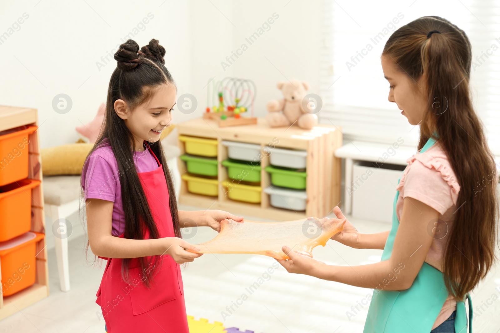 Photo of Happy girls playing with slime in room