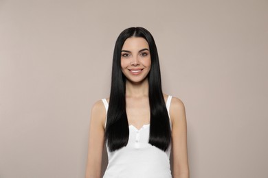 Photo of Beautiful young woman with long straight hair on beige background