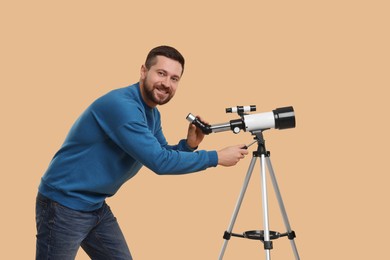 Happy astronomer with telescope on beige background