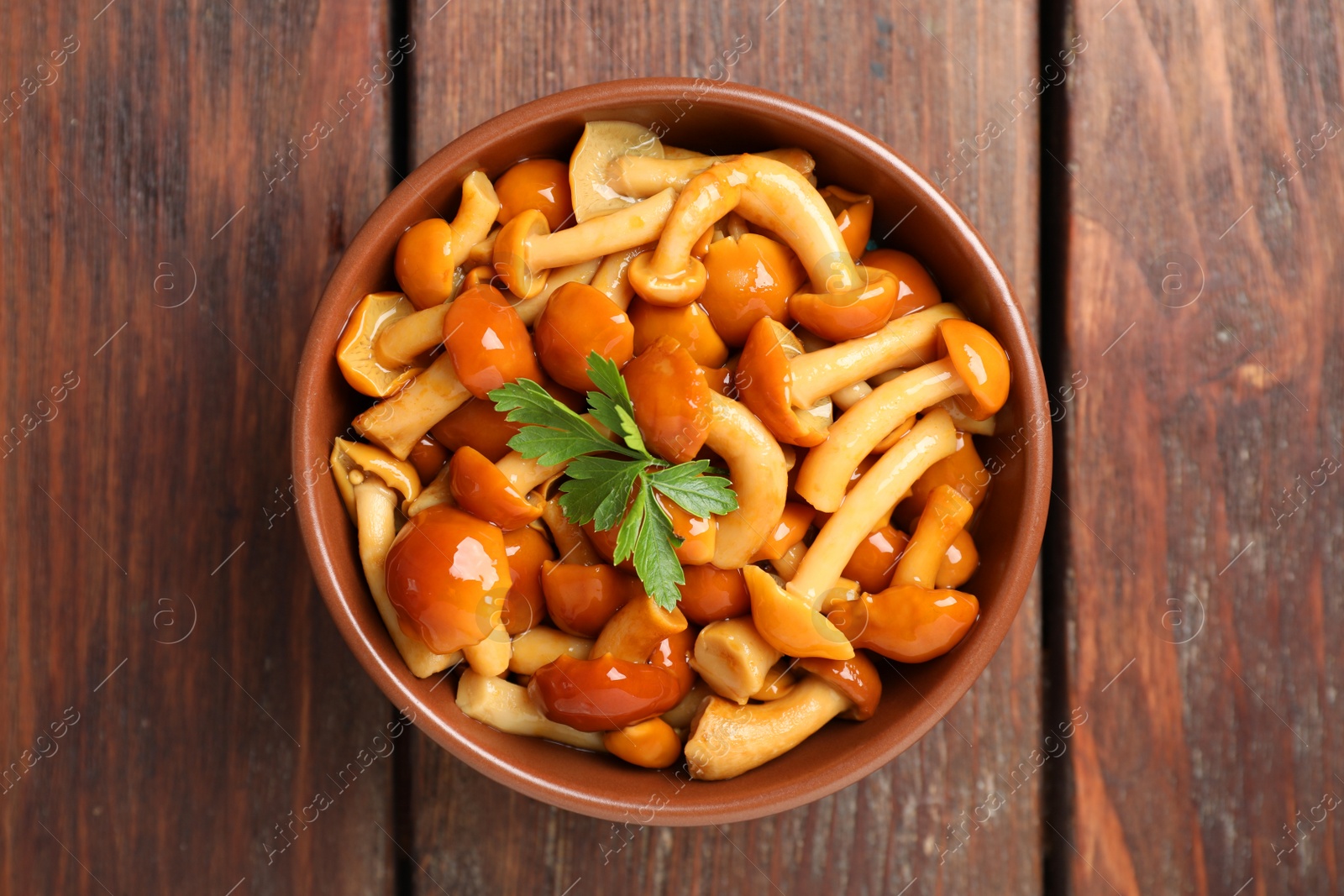 Photo of Tasty marinated mushrooms in bowl on wooden table, top view