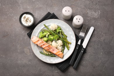 Photo of Healthy meal. Piecegrilled salmon, vegetables, asparagus and rosemary served with sauce on grey textured table, flat lay