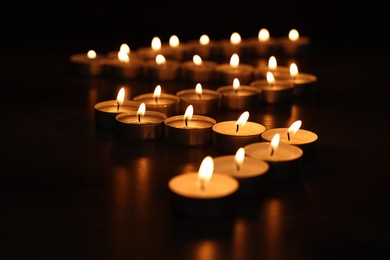 Burning candles on surface in darkness, closeup