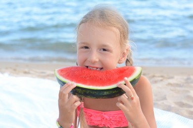 Photo of Cute little girl eating juicy watermelon on beach