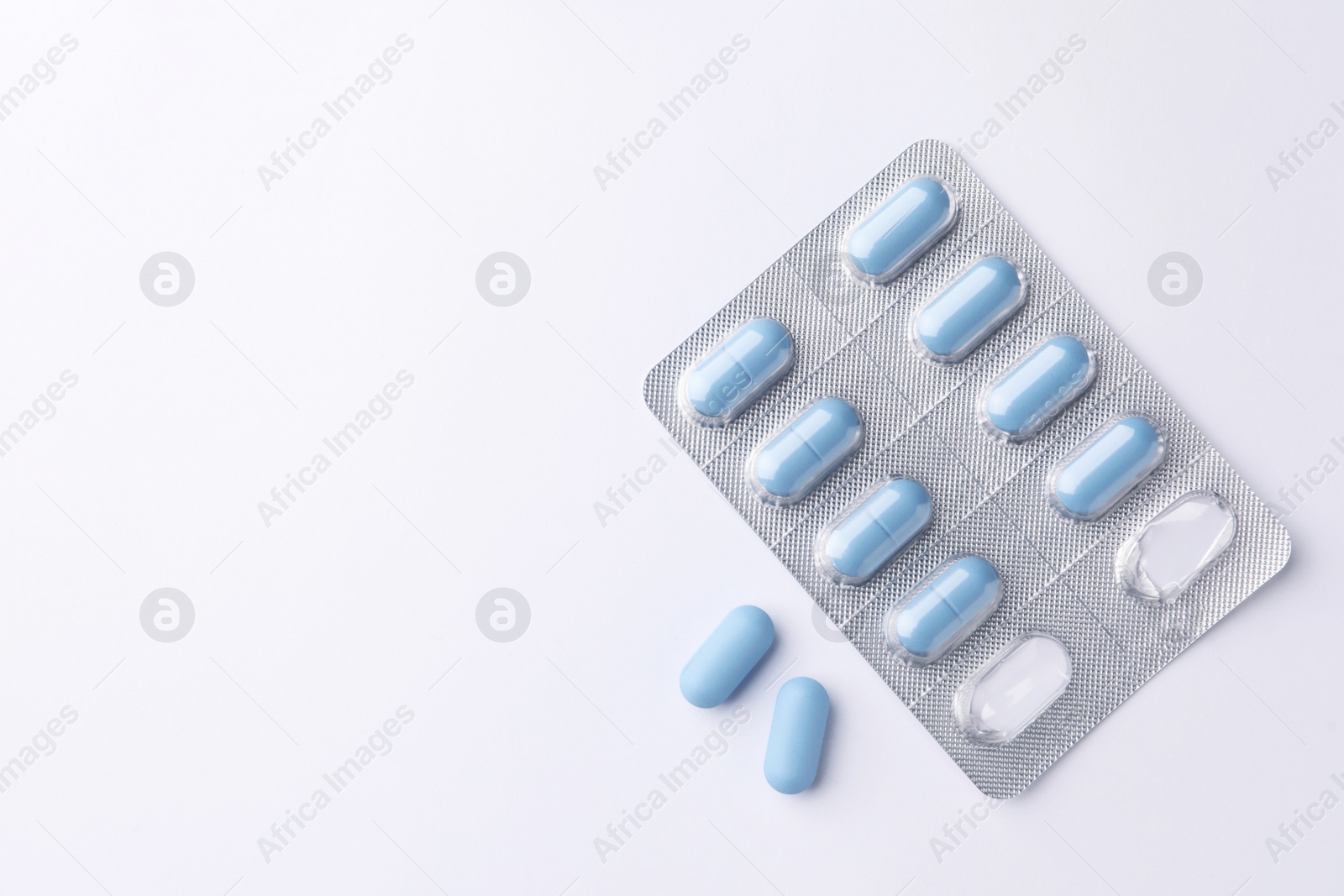 Photo of Pills and space for text on white background, top view. Potency problem