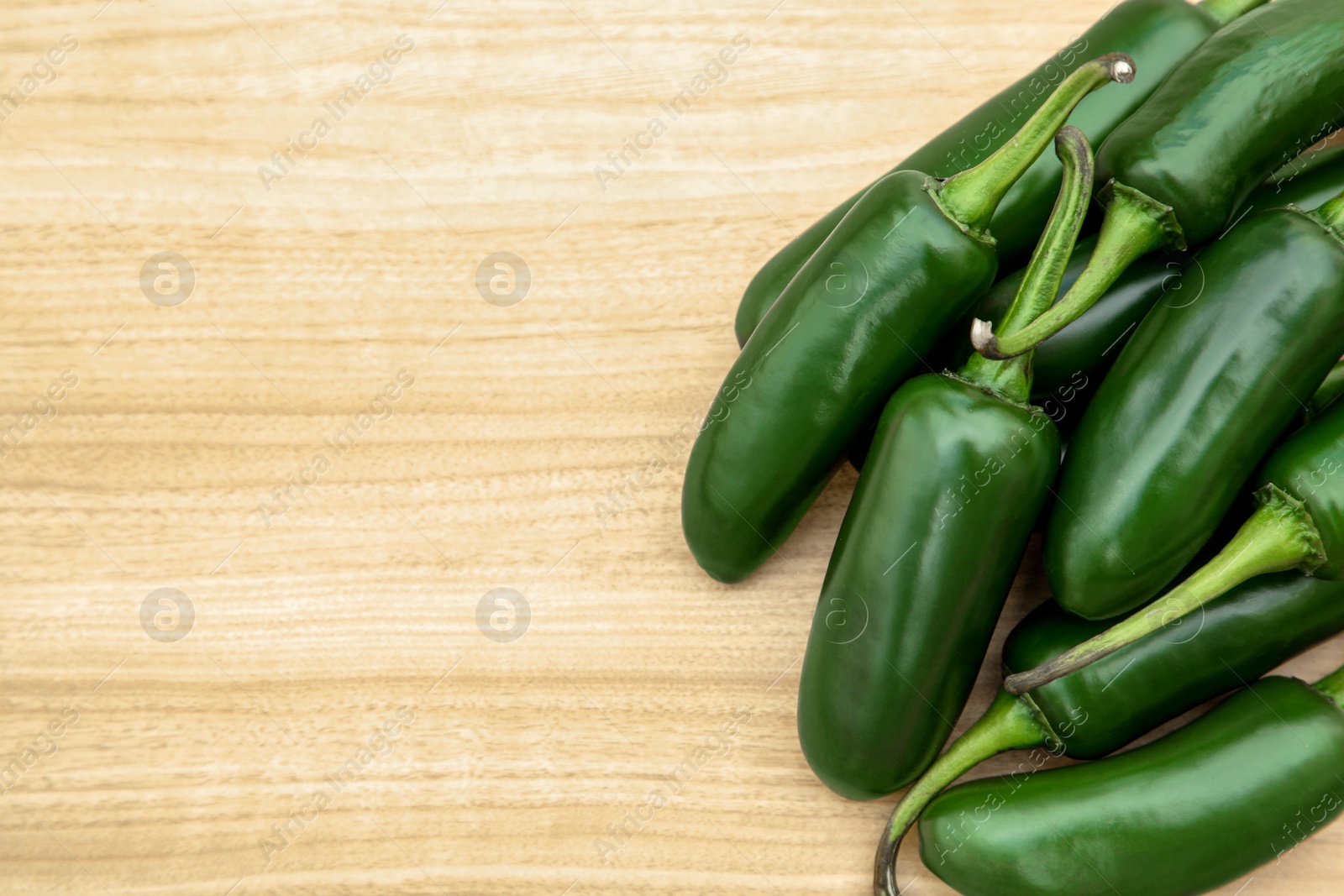 Photo of Fresh ripe green jalapeno peppers on wooden table, flat lay. Space for text