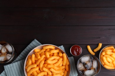 Crunchy cheesy corn snack, ketchup and refreshing drink on wooden table, flat lay. Space for text