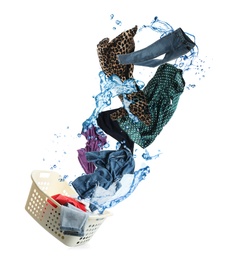 Different clothes with water splash falling into laundry basket against white background