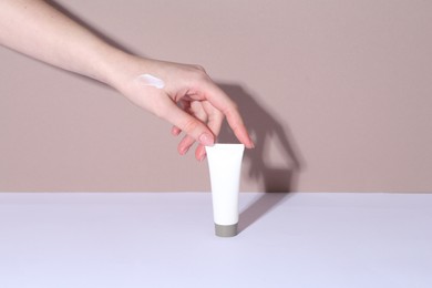 Woman with tube of cream on color background, closeup