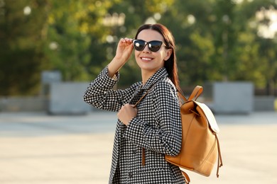 Beautiful young woman with stylish backpack on city street