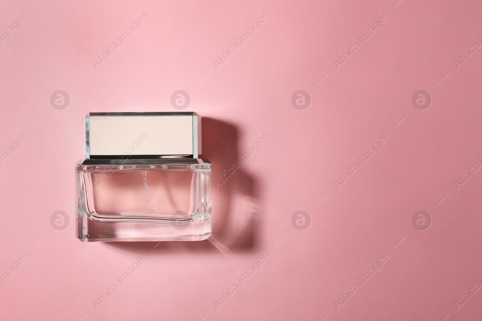 Photo of Bottle of perfume on color background, top view